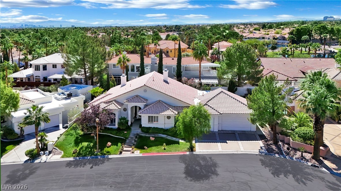 Mature palms and a tile roof define this classic desert residence sitting along a curved street.