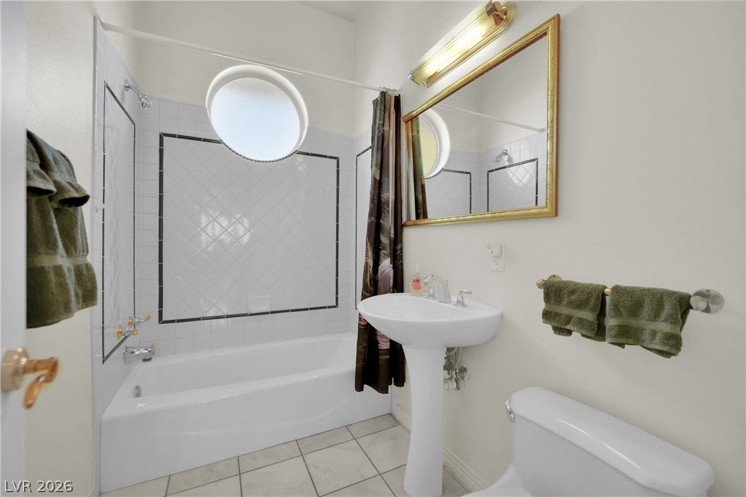 Tiled flooring and a classic pedestal sink define this bright bathroom space.