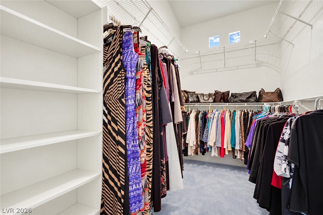 Ample built-in shelving and wire racks maximize storage space in this carpeted walk-in closet.