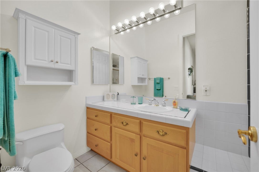 An accommodating vanity area features integrated tile countertops and matching cabinetry.