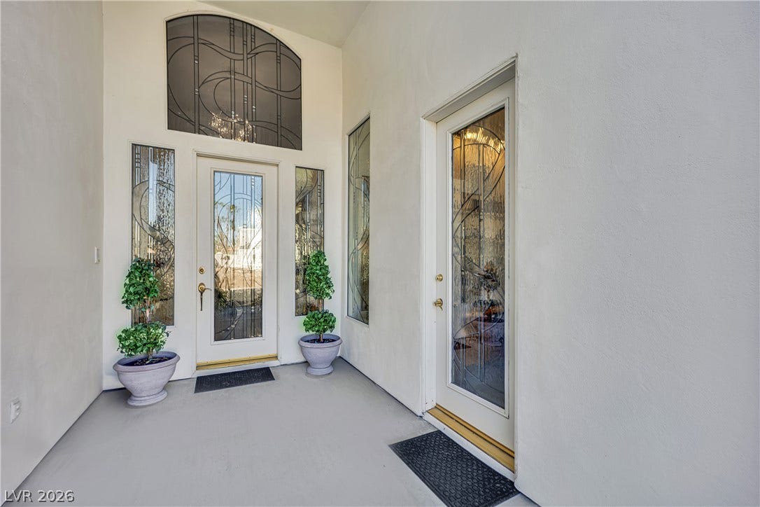 Leaded glass doors set in smooth stucco walls create a grand entry experience.