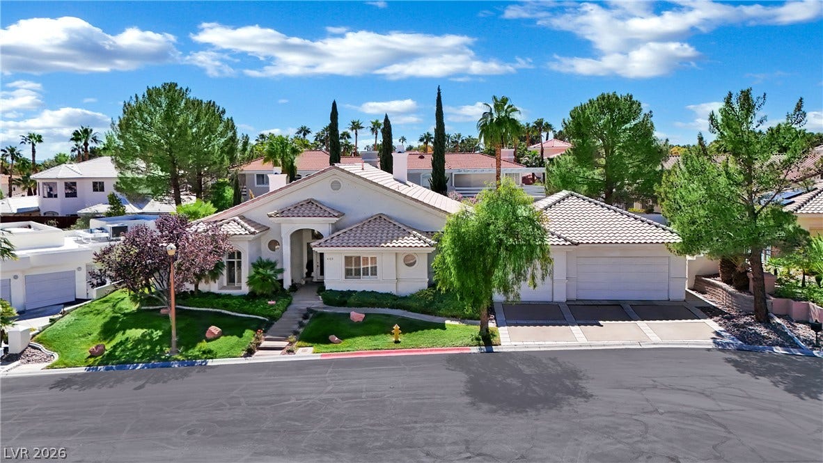 Lush manicured lawns and mature trees frame this single-level residence featuring a classic tile roof.
