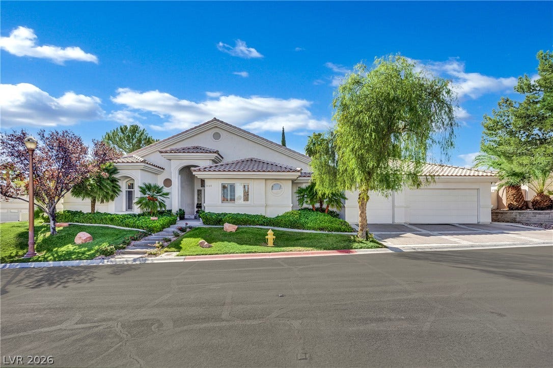 Manicured landscaping framing a classic stucco facade with Spanish tile roof accents.