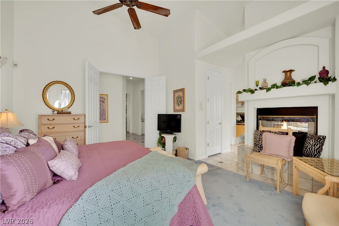 Vaulted ceilings and a cozy fireplace define this comfortable primary bedroom suite.
