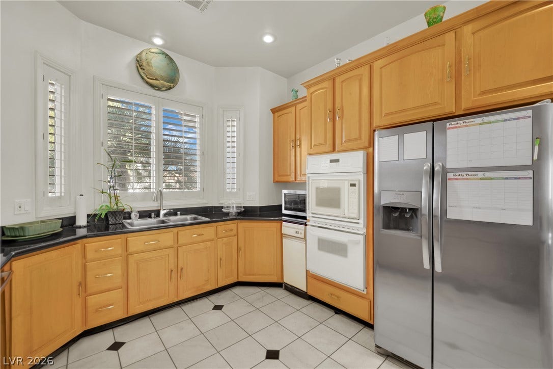 Ample wooden cabinetry and dark solid-surface countertops line this functional corner kitchen space.