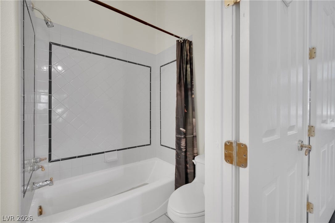 Tiled wall detailing surrounds the tub and shower combination in this full bathroom.