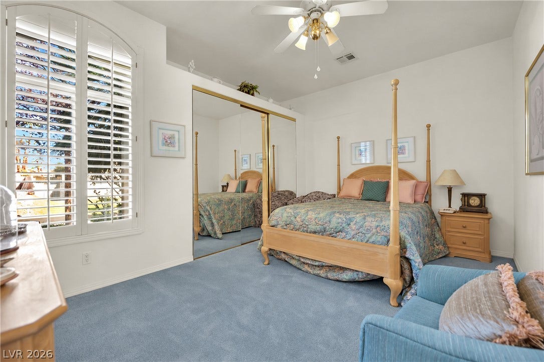 Sunlight filters through elegant plantation shutters in this bedroom featuring carpet flooring.