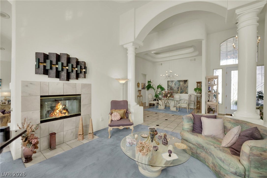 Grand architectural archways and high ceilings frame this spacious living area with a fireplace.