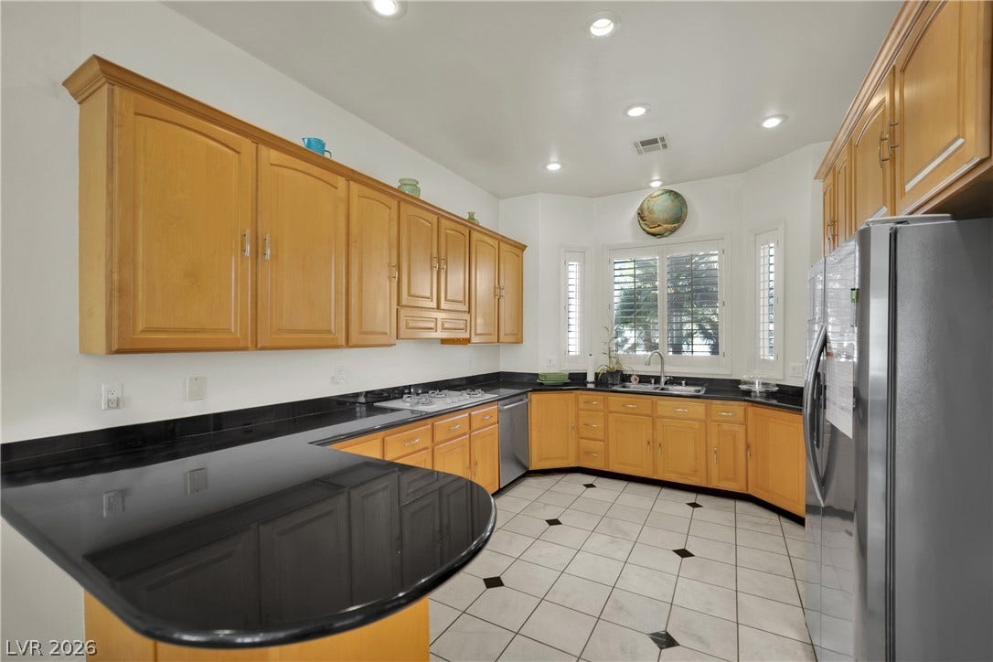Polished granite countertops complement warm wood cabinetry and classic tiled floors in this functional kitchen.