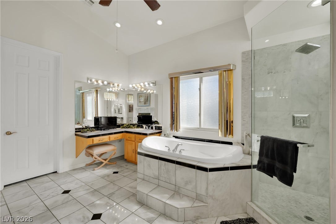 Polished tile flooring pairs with a deep soaking tub and custom glass-enclosed shower.