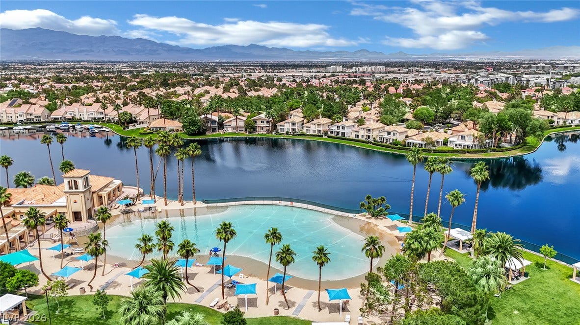 Lush palm trees line a community lagoon set against a backdrop of mountains.
