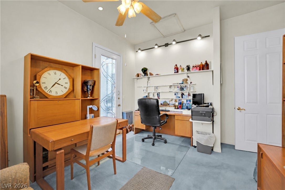 A functional home workspace features recessed lighting and carpet flooring.