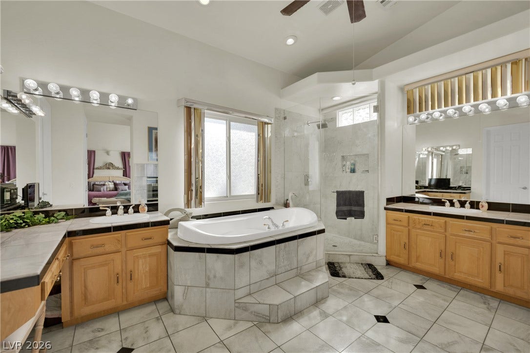 A spacious bathroom features dual vanities, a tiled soaking tub, and a separate walk-in shower.