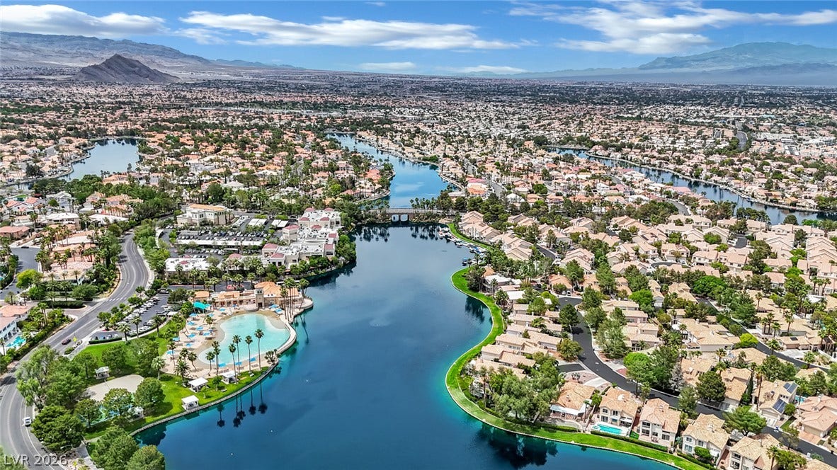 A quiet lake winds through a serene residential community set against distant mountain ranges.