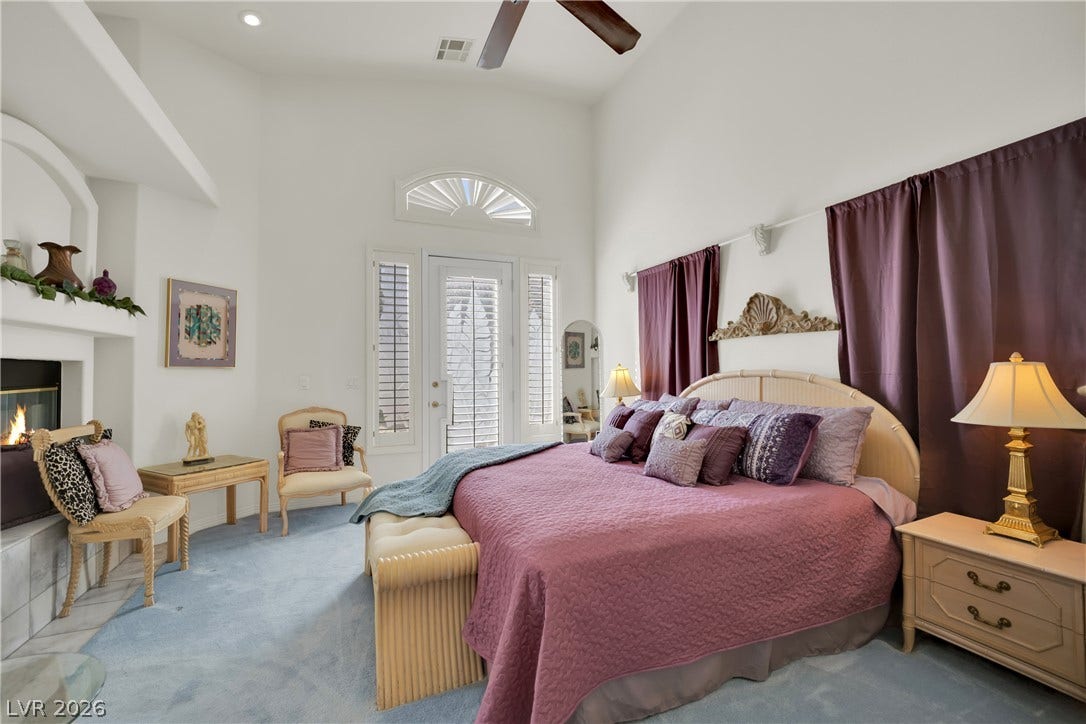 A spacious bedroom features towering ceilings, a cozy fireplace, and direct backyard access.