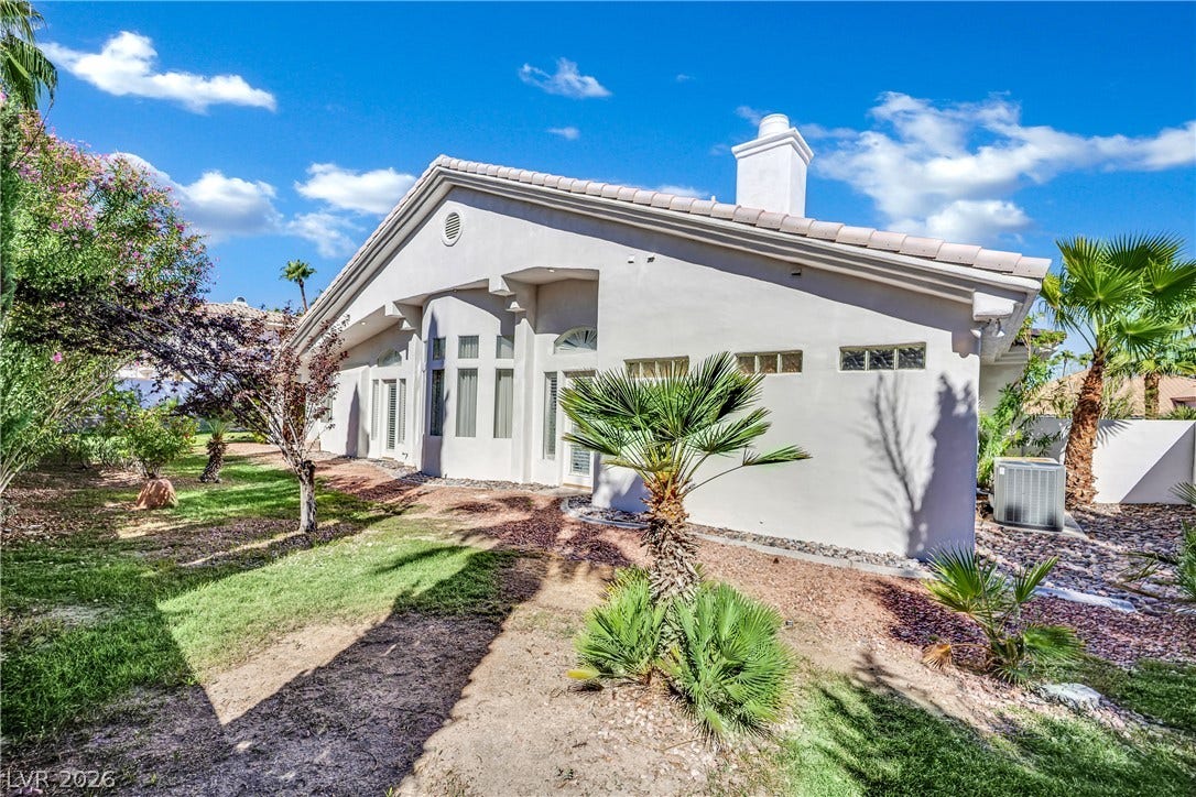 Palm trees frame the stucco exterior of this modern desert residence under blue skies.