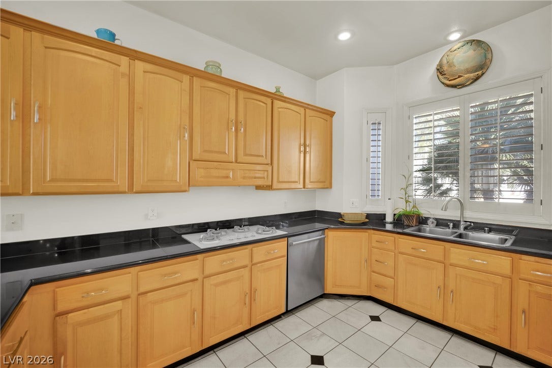 Ample cabinetry and polished stone countertops wrap this kitchen, complete with recessed lighting and tile flooring.