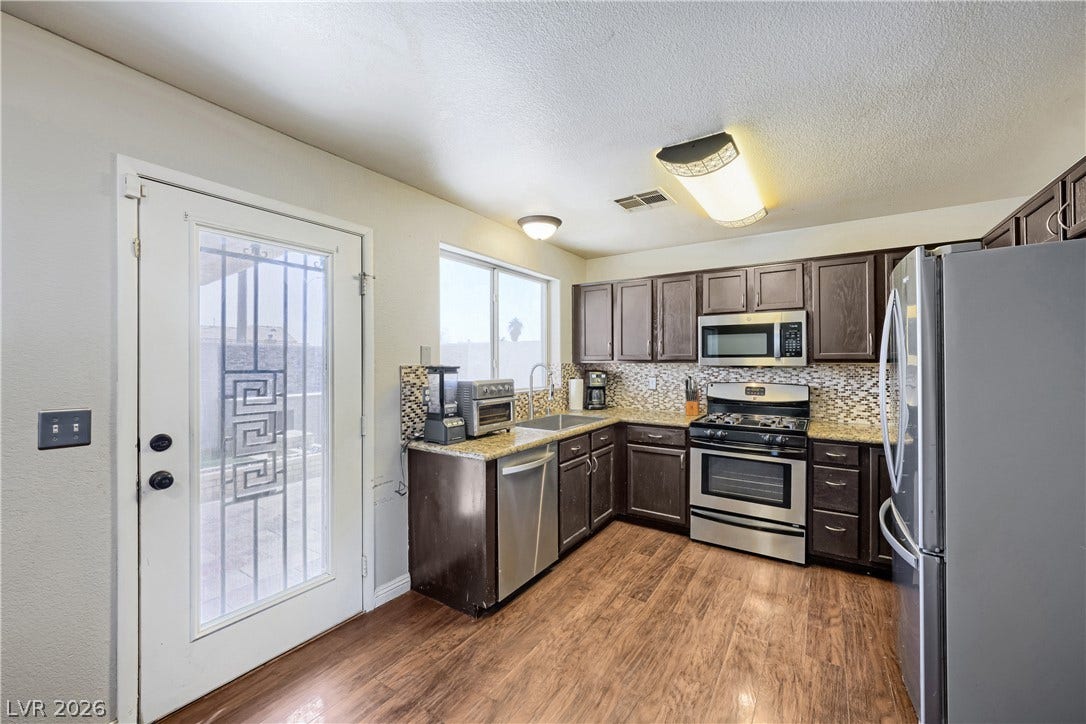 3536 Golden Pedal Street, Las Vegas, NV 89129 Rich wood cabinetry and warm-toned flooring define this well-appointed kitchen space.