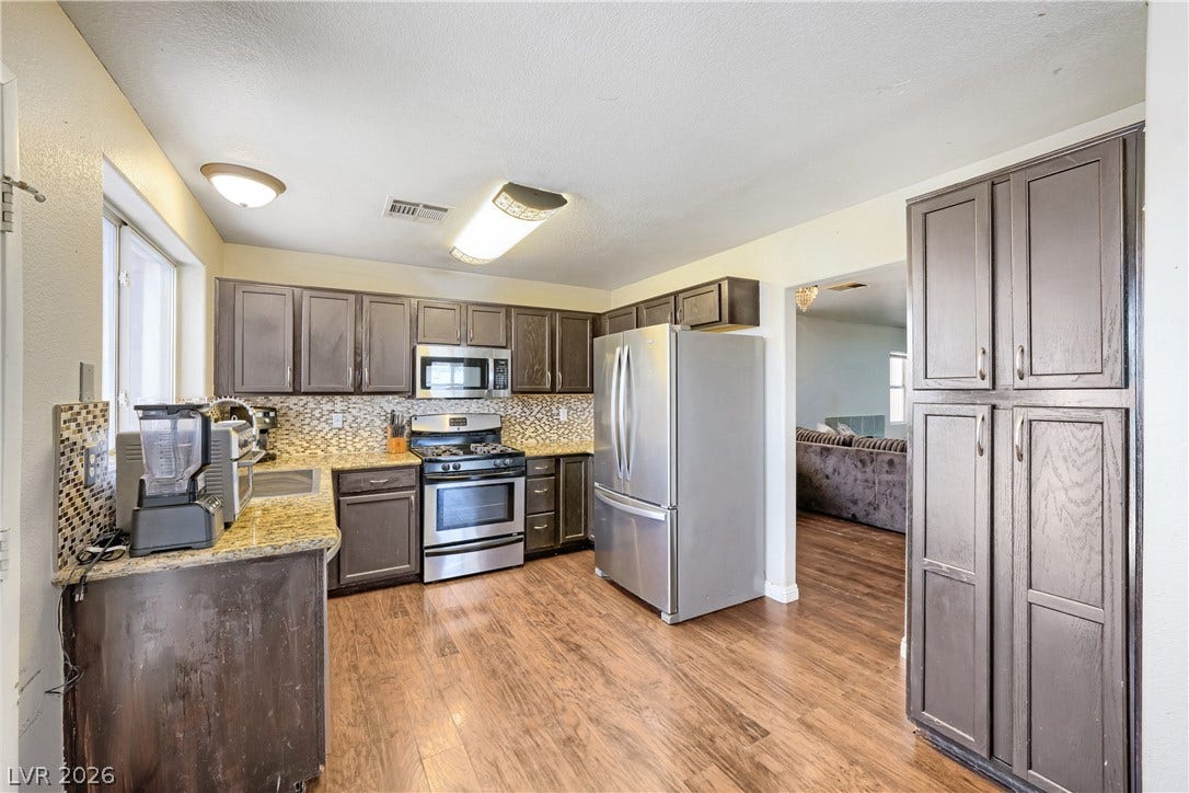 3536 Golden Pedal Street, Las Vegas, NV 89129 Gleaming hardwood floors and stone countertops anchor this inviting and functional kitchen space.