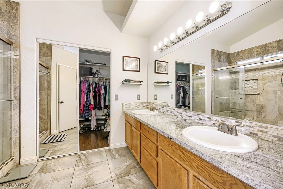 3536 Golden Pedal Street, Las Vegas, NV 89129 Double sinks accent a granite vanity alongside a walk-in shower and tiled floors.