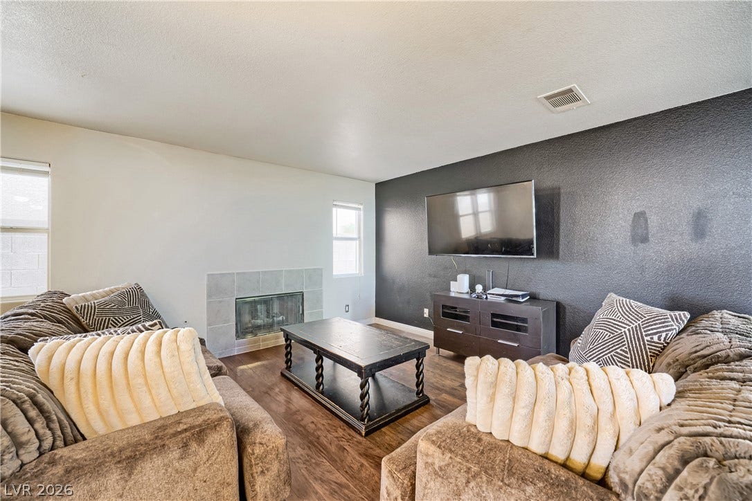 3536 Golden Pedal Street, Las Vegas, NV 89129 Rich wood flooring runs throughout this inviting living space anchored by a tiled fireplace.