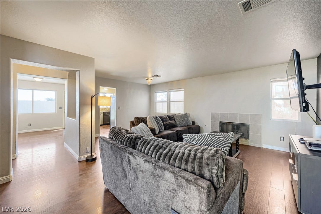 3536 Golden Pedal Street, Las Vegas, NV 89129 Rich wood flooring runs throughout this inviting living space anchored by a tiled fireplace.