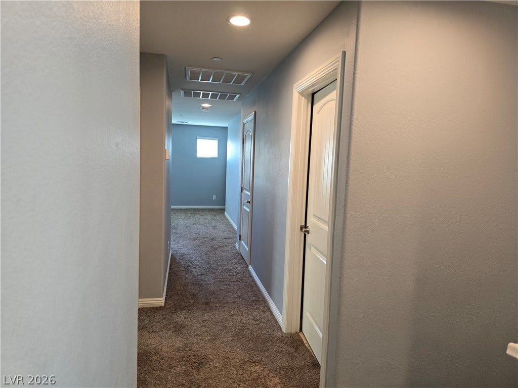 2926 Tremont Avenue, Henderson, NV 89052 A long hallway with recessed lighting leads past several rooms to a bright window.