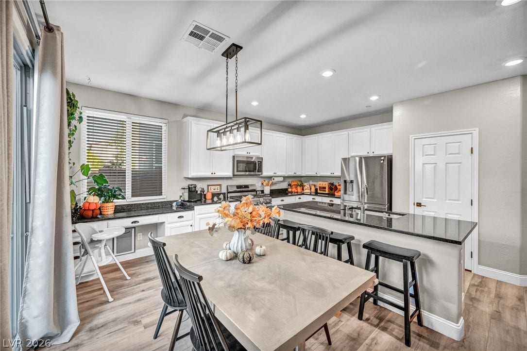 Granite countertops and clean white cabinetry anchor this modern kitchen and dining area.