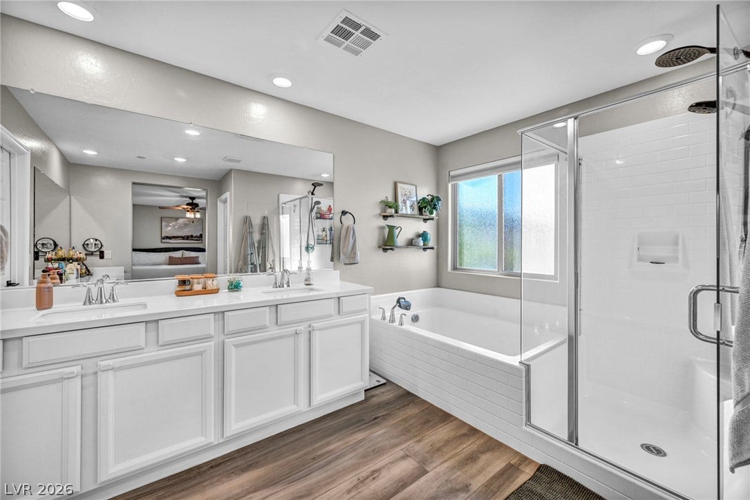 A spacious double vanity and a glass-enclosed shower complement the large soaking tub.