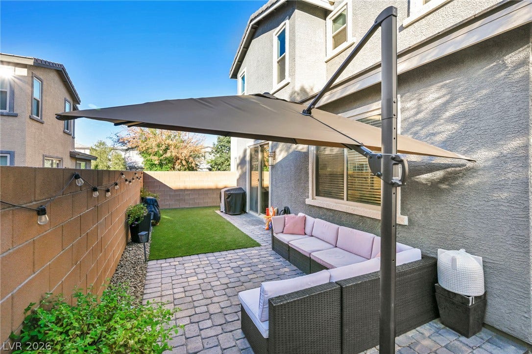 An inviting paved patio borders a manicured lawn enclosed by block wall fencing.