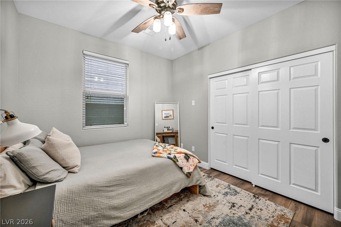 A quiet bedroom features warm wood flooring and a large closet with sliding doors.