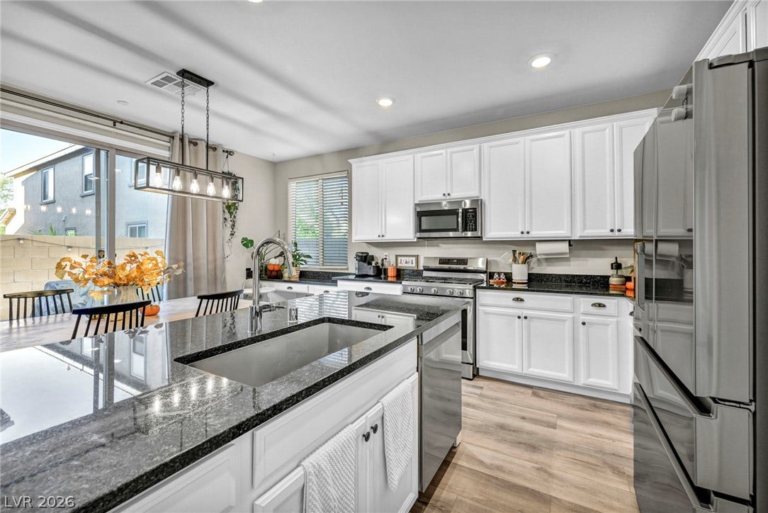 Polished granite countertops and classic white cabinetry define this beautifully appointed kitchen workspace.