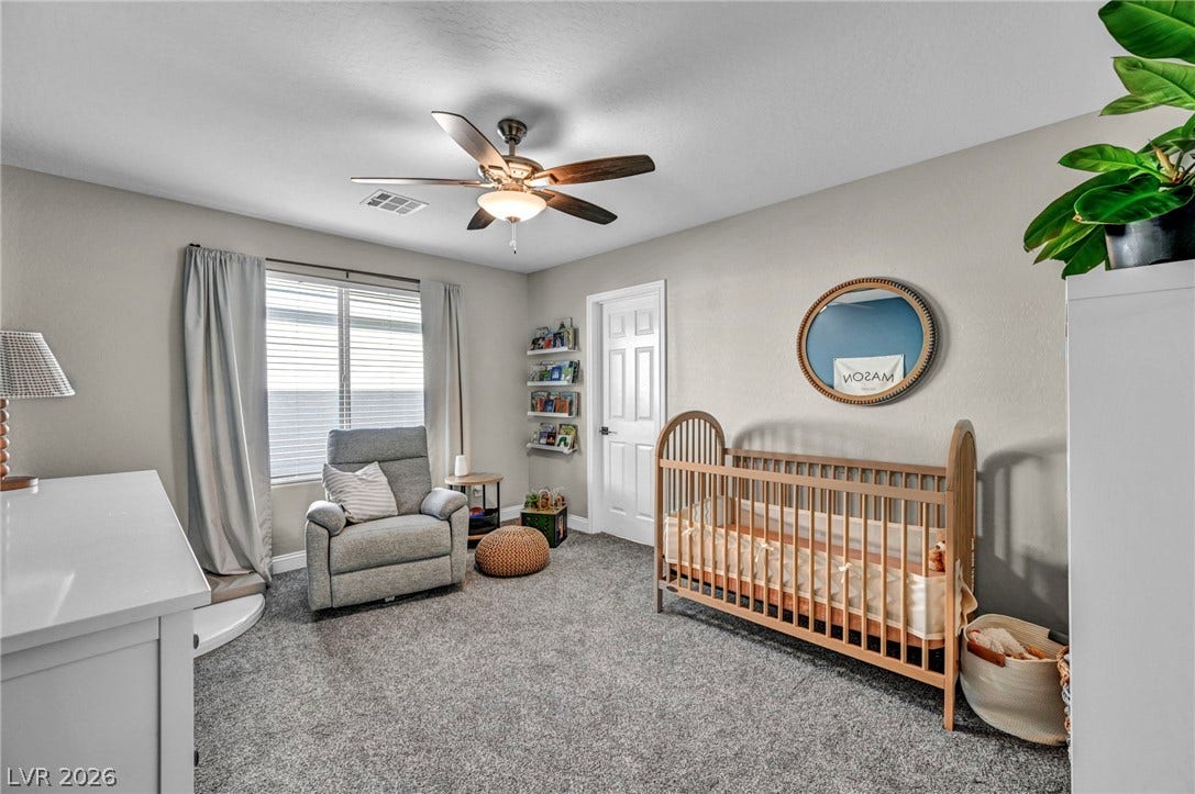 Plush carpet flooring and a wide window with integrated shutters define this versatile room.