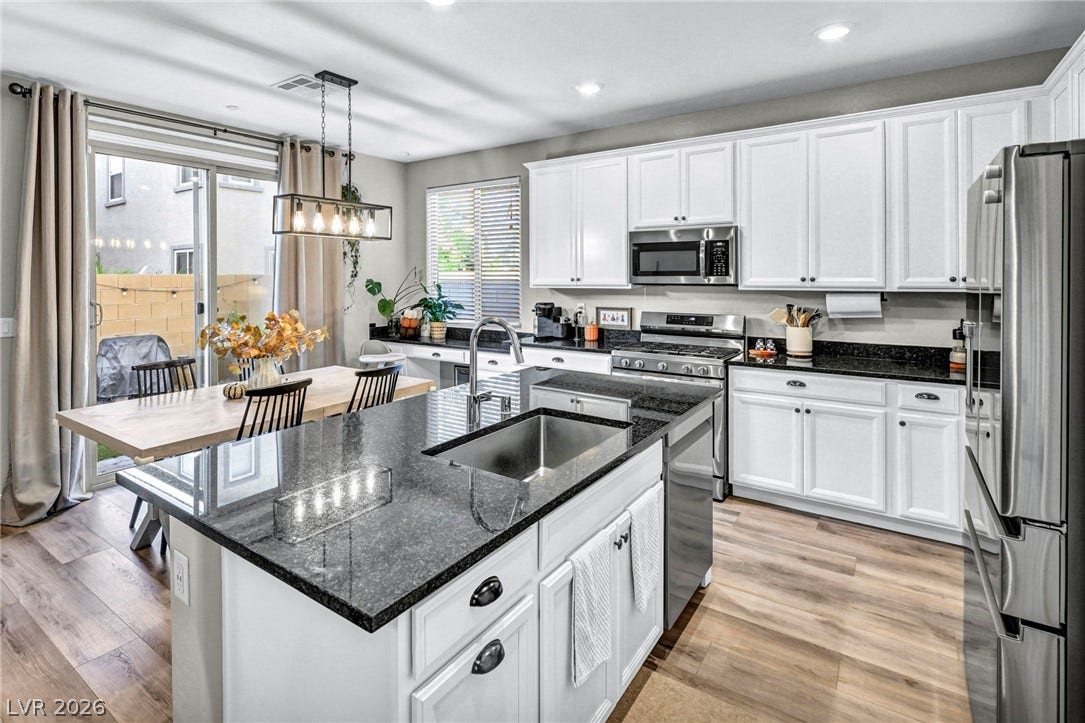 Polished granite countertops and classic white cabinetry define this bright, open kitchen space.
