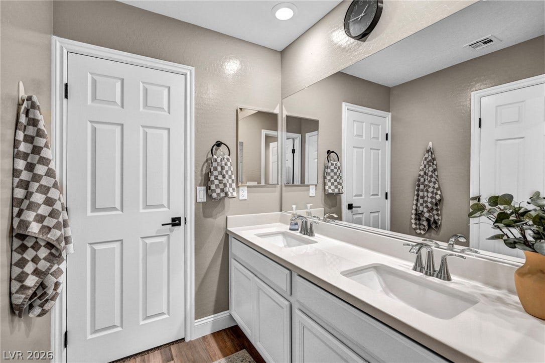 Double vanities sit beneath an expansive mirror in this well-appointed washroom.