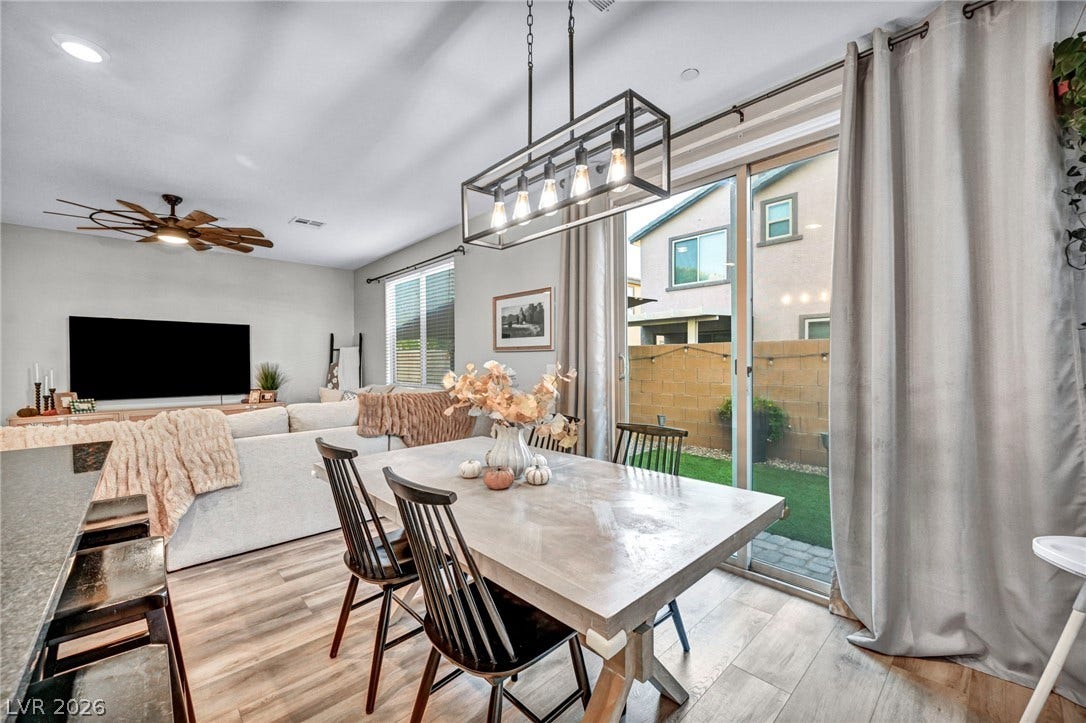 Sunlight streams through sliding glass doors onto beautiful wood flooring in this open dining area.
