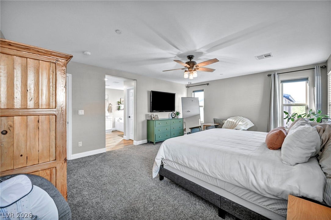 Plush carpeting anchors this spacious bedroom featuring an attached bath and generous natural light.
