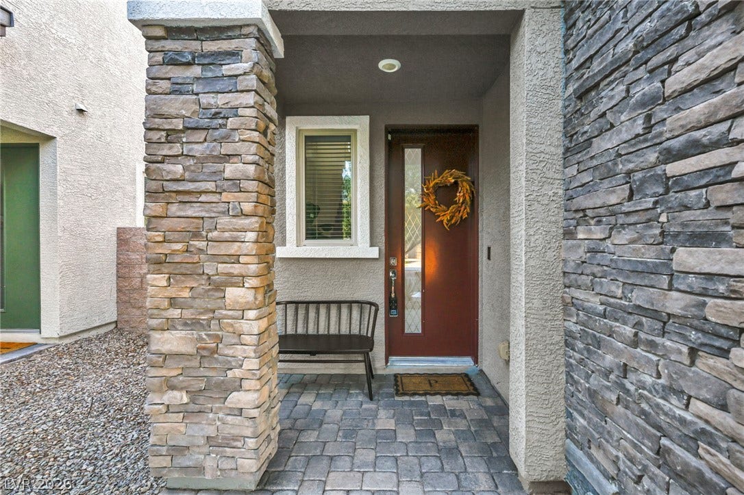 Textured stone pillars flank a welcoming entryway paved with classic cobblestone tiles.