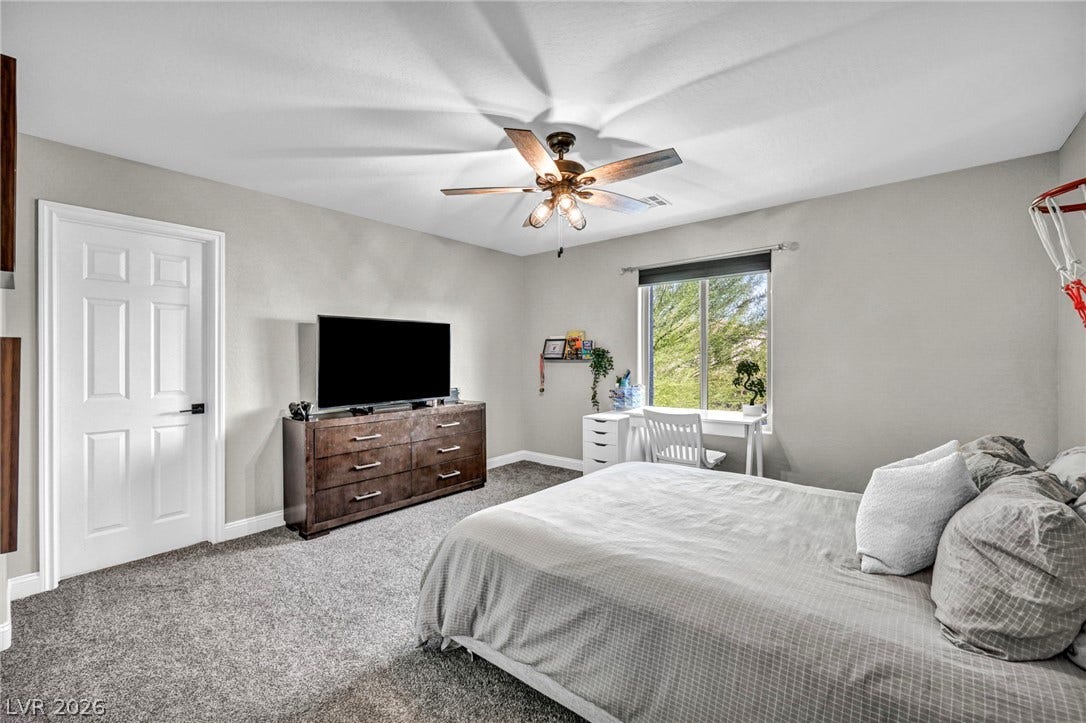 Plush carpeting and a wide window frame garden views in this serene bedroom.