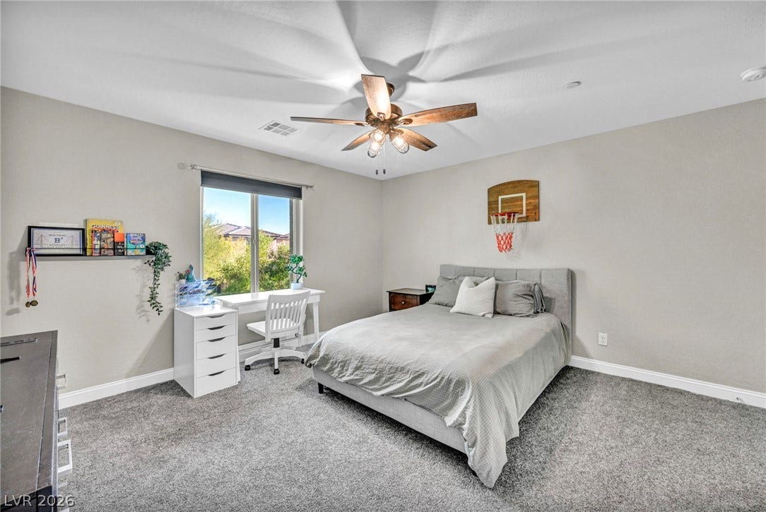 A spacious secondary bedroom features soft wall-to-wall carpeting and a wide window looking outside.