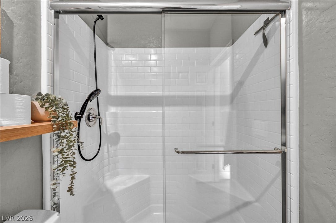 A modern walk-in shower features classic subway tile and sliding glass doors.