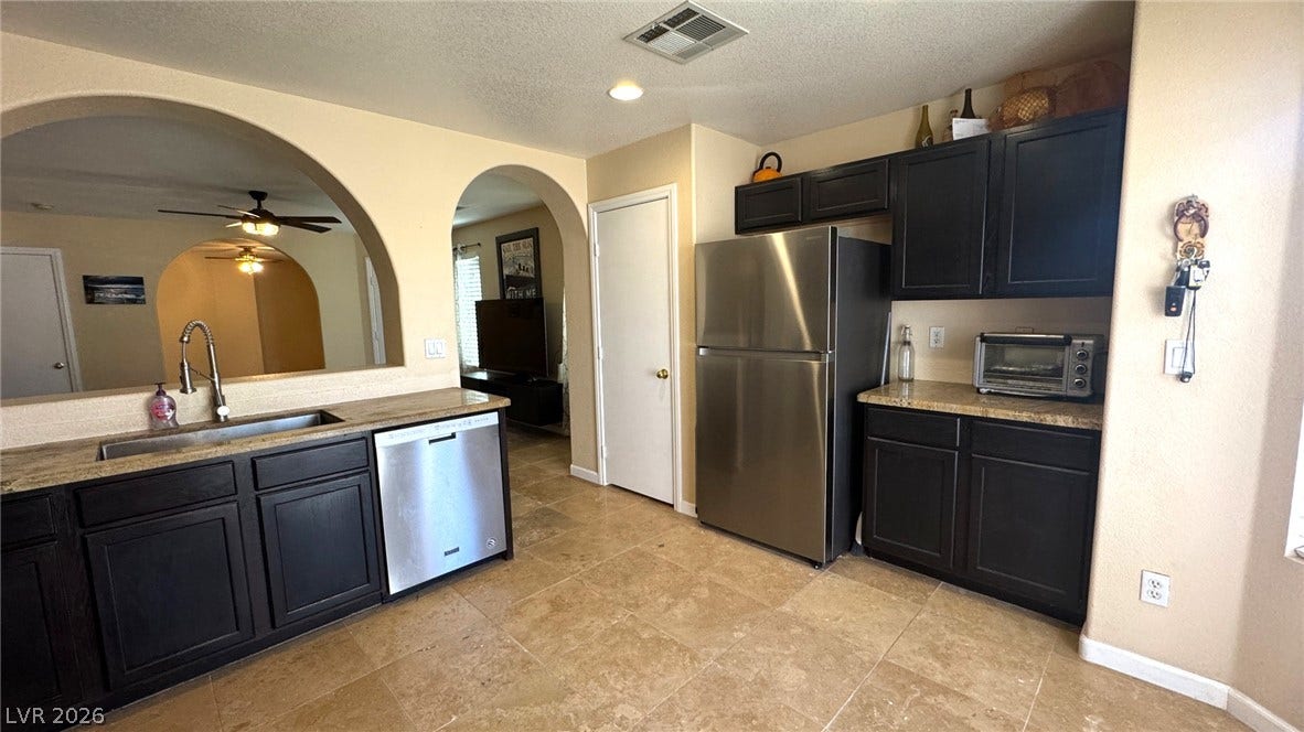 Dark cabinetry and stainless steel appliances complement the stone tile flooring.