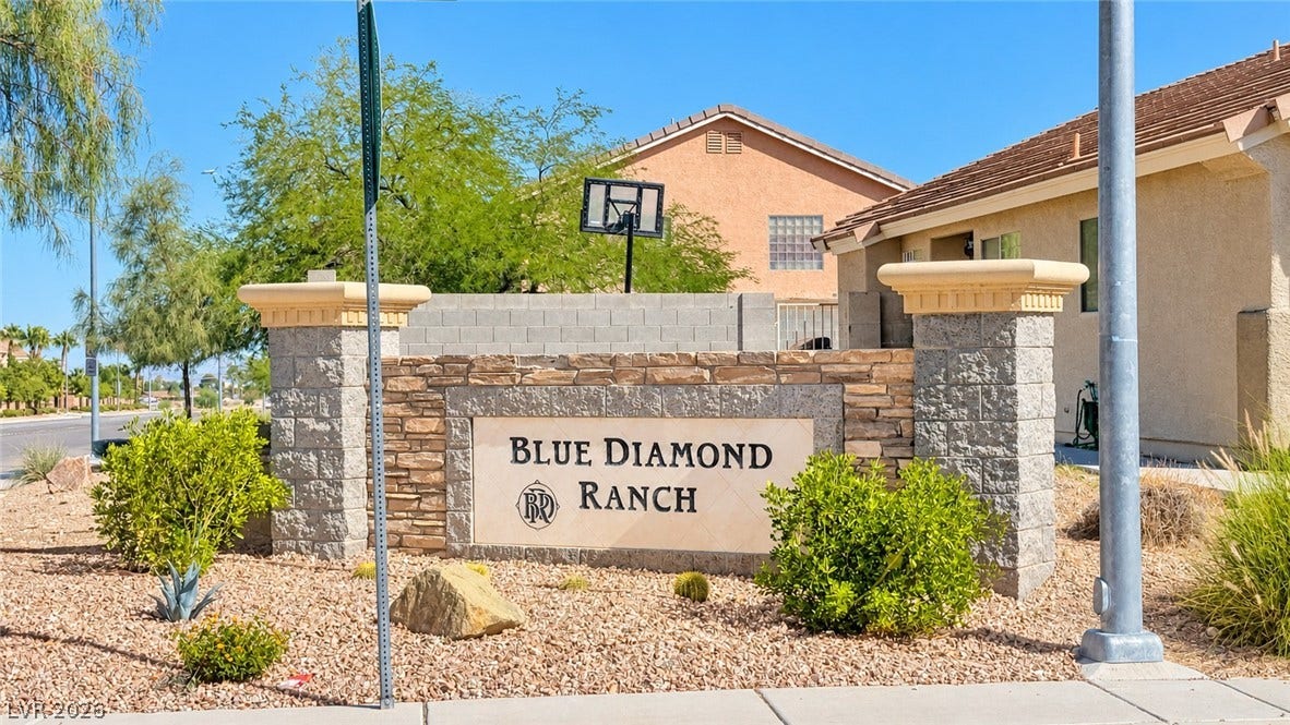 A stone monument sign marks the community entrance amid desert landscaping.