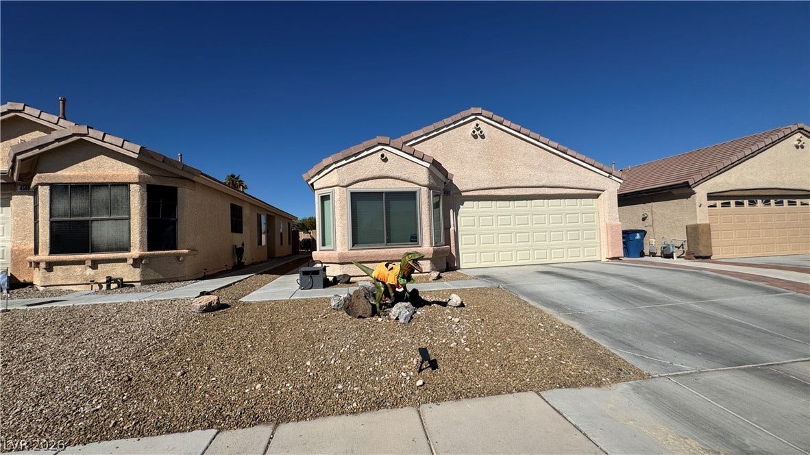 Low-maintenance desert landscaping frames the stucco exterior of this single-story home with tiled roofing.