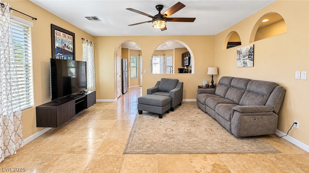 Elegant arched doorways frame views to the kitchen from this spacious living area.