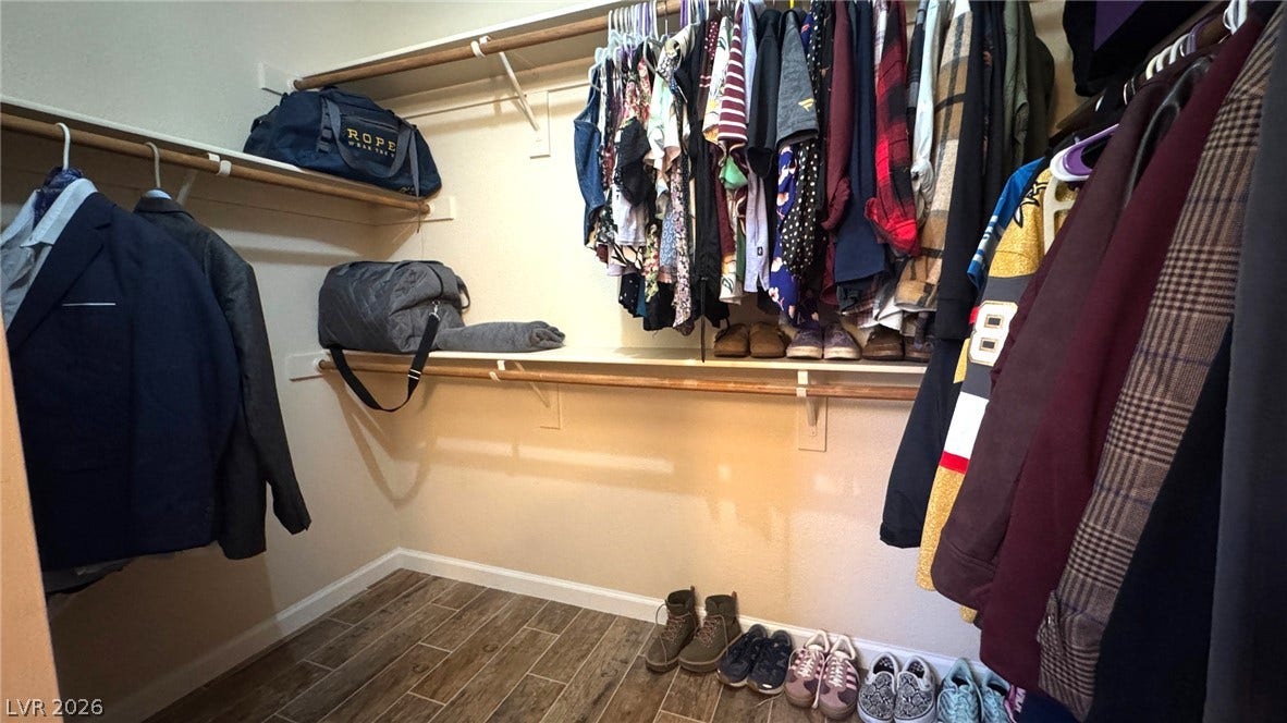 Ample built-in shelving and hanging rods maximize storage within this wood-look tile walk-in closet.