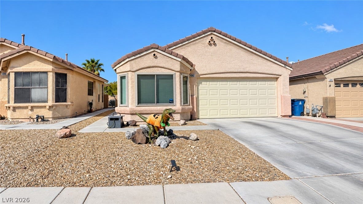 A classic stucco exterior features a tiled roof and a neat concrete driveway.