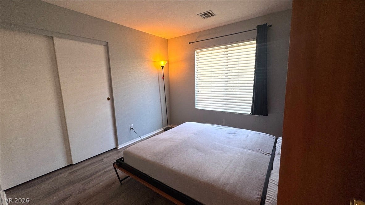 Smooth wood-plank flooring pairs with a large window and sliding closet doors.