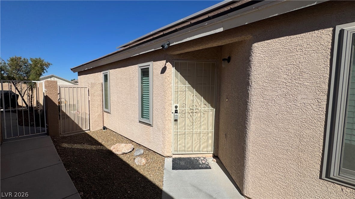 An inviting entryway presents textured stucco walls and a secure gated side yard access.