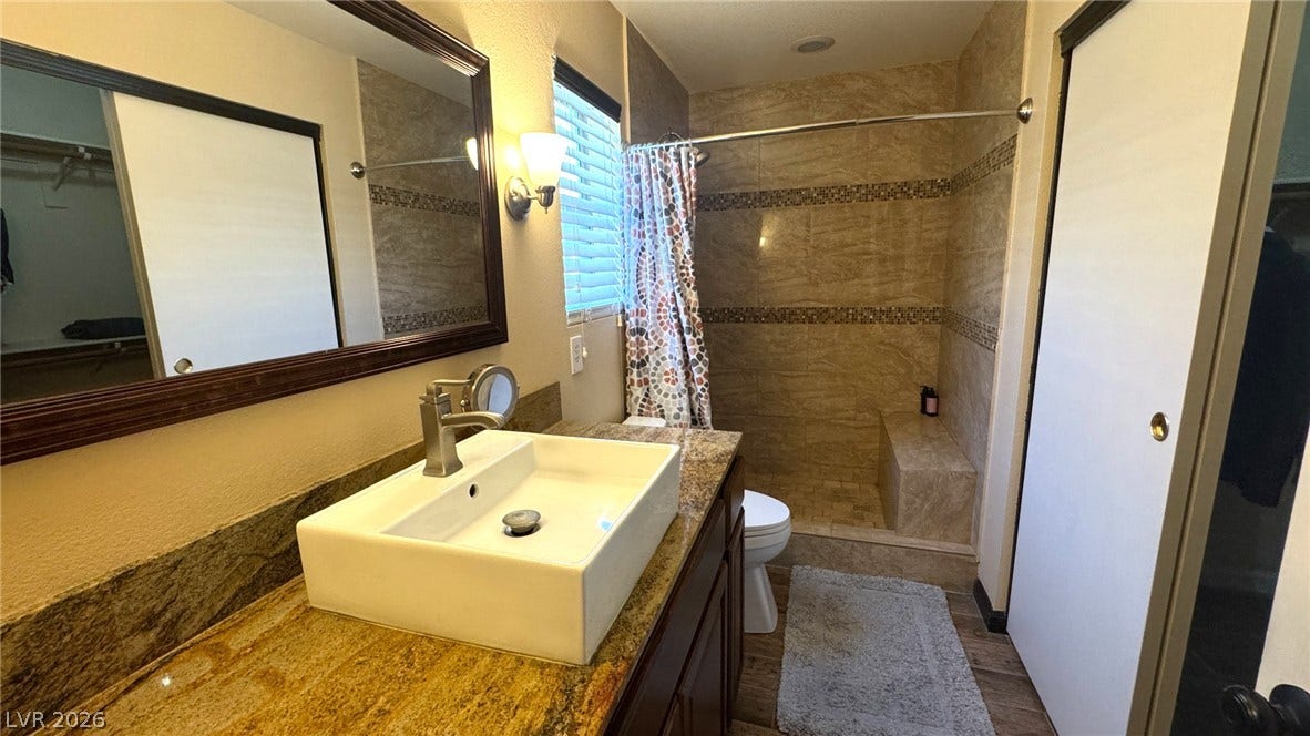 A modern vanity with stone counters complements the beautifully tiled walk-in shower.